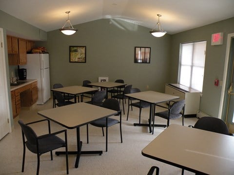 a multipurpose room with tables and chairs and a kitchen