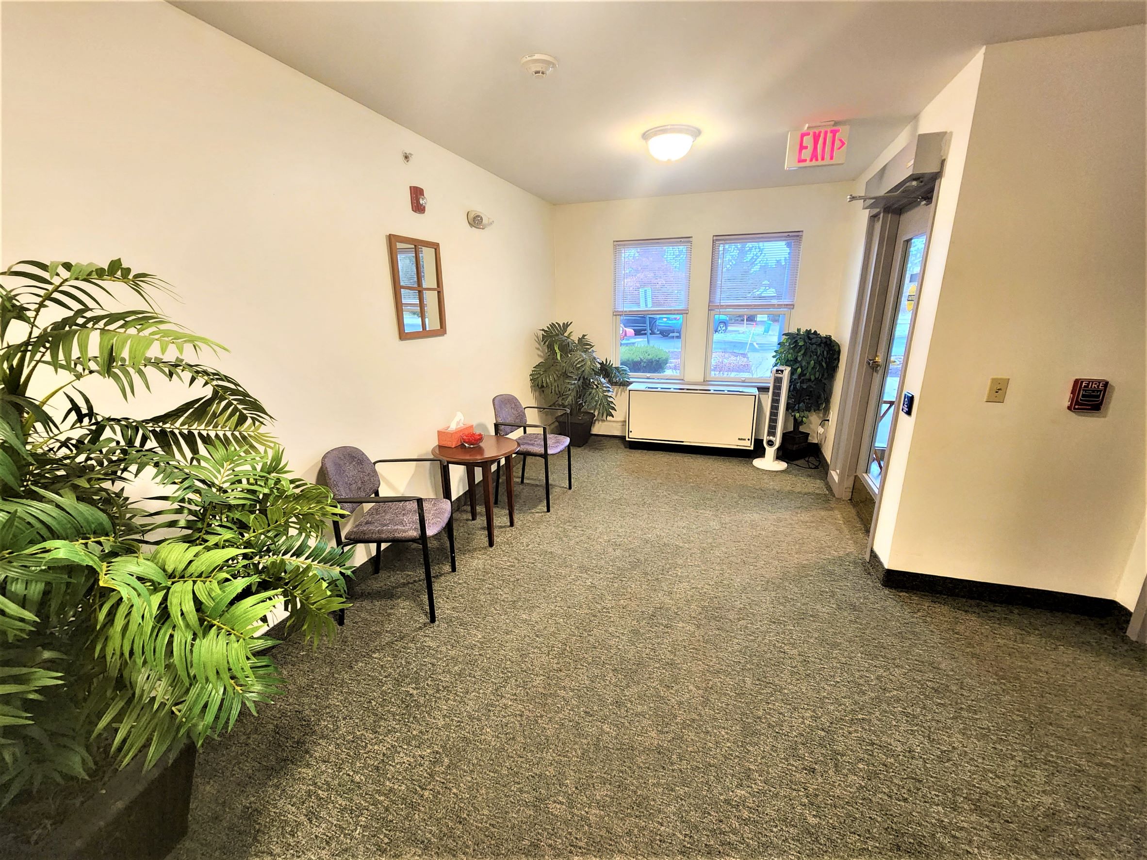 a corridor with a table and chairs and a exit sign