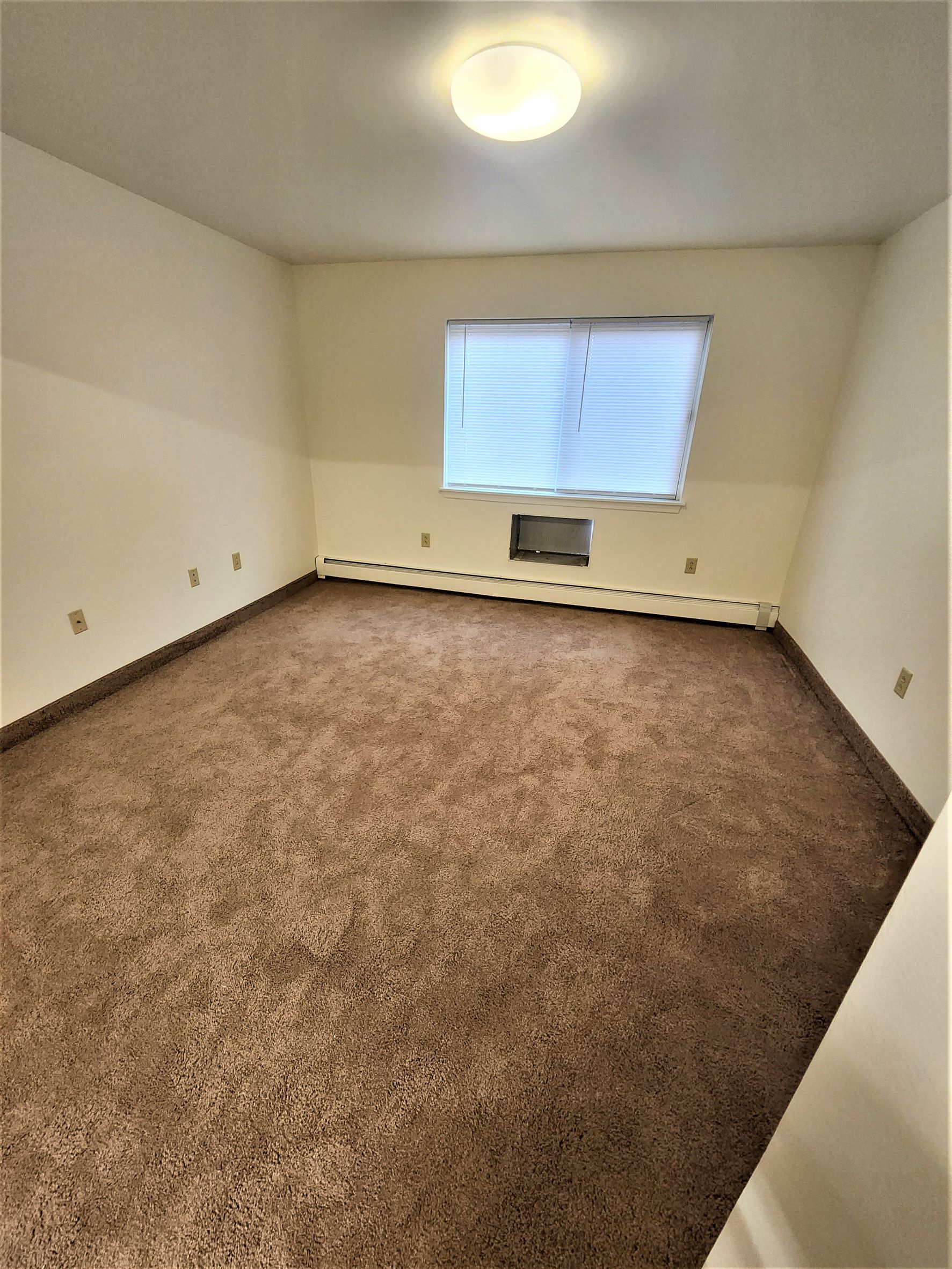 an empty room with a window and a carpet