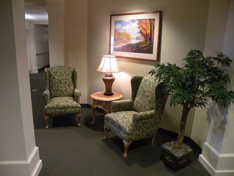 a small living room with chairs and a lamp