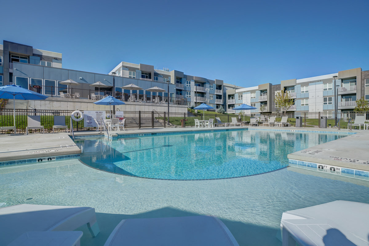 a large swimming pool with apartments in the background