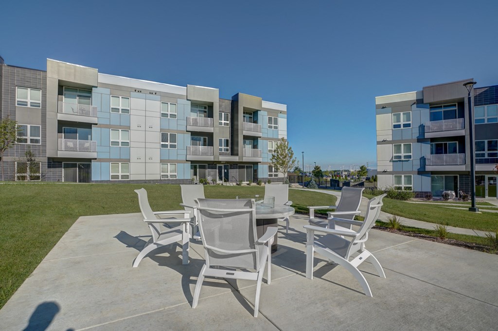a patio with a table and chairs in front of an apartment building
