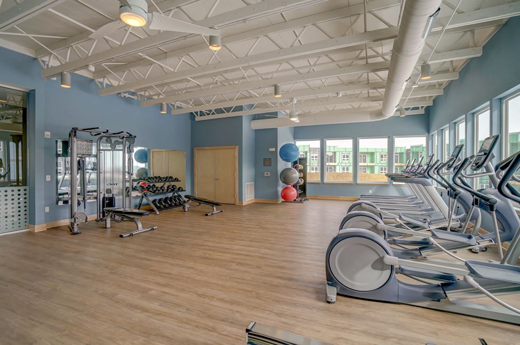 a gym with cardio machines and weights on a wooden floor