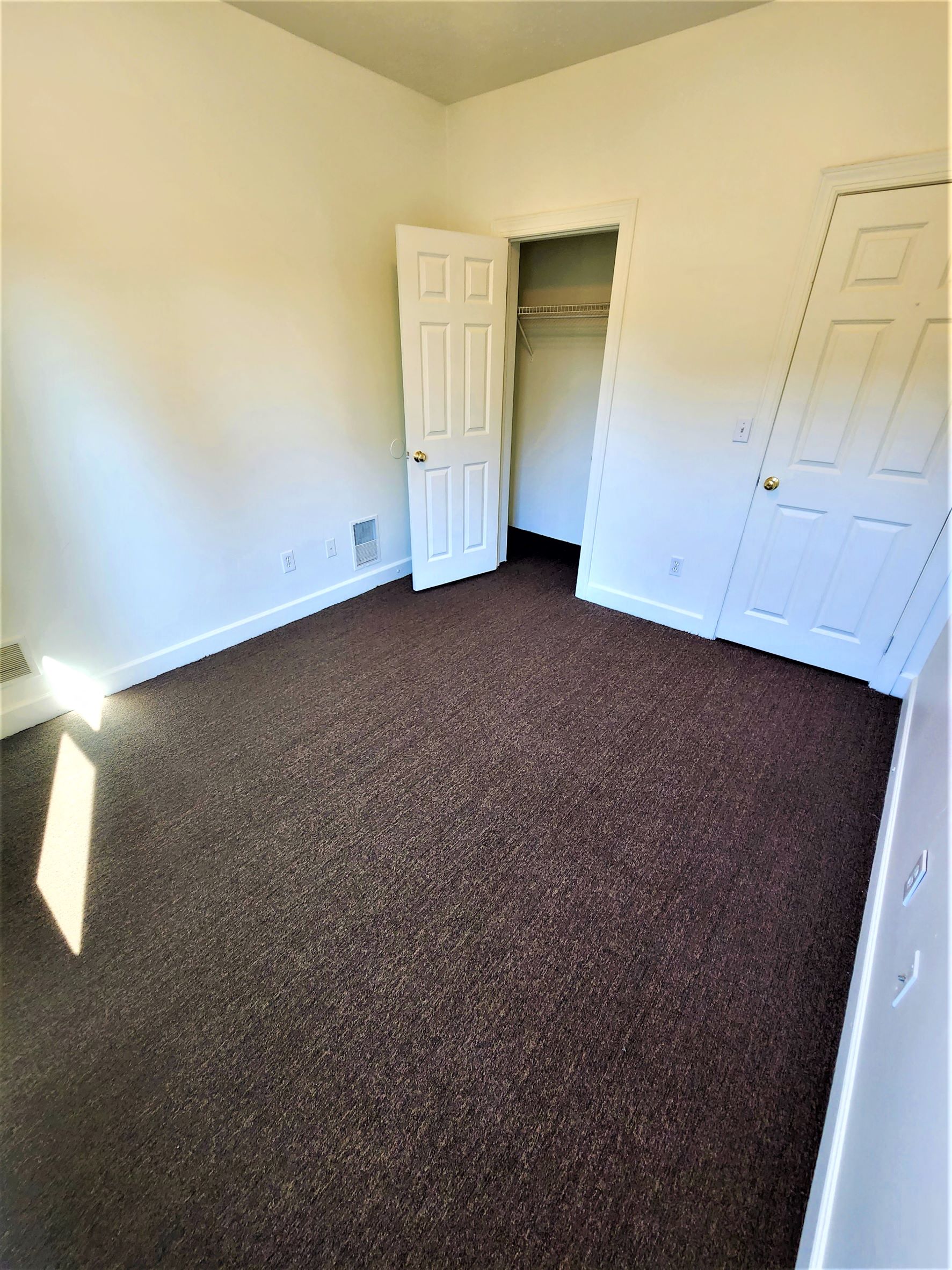 a bedroom with a carpeted floor and a door to a closet