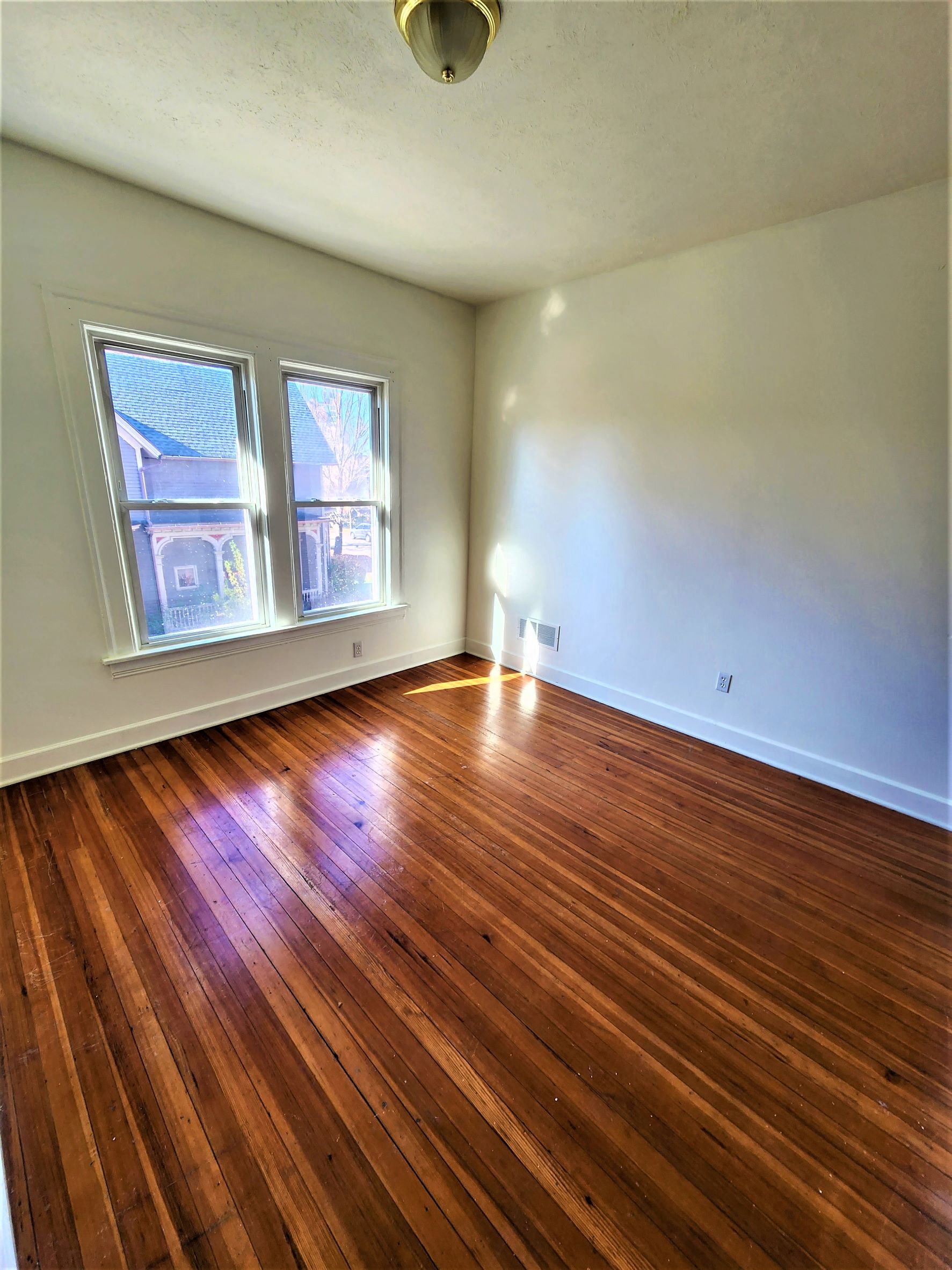 an empty living room with wood floors and white walls