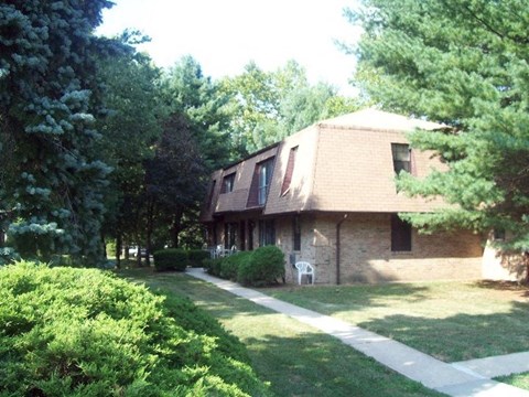 A house with a brown roof and a white chair in front of it.