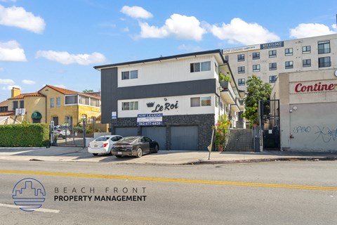 A building with a sign that says Le Roi is in front of a building that says Conine.