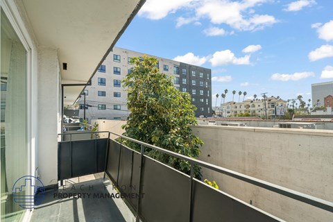 A balcony with a railing and a tree in front of a multi-story building.