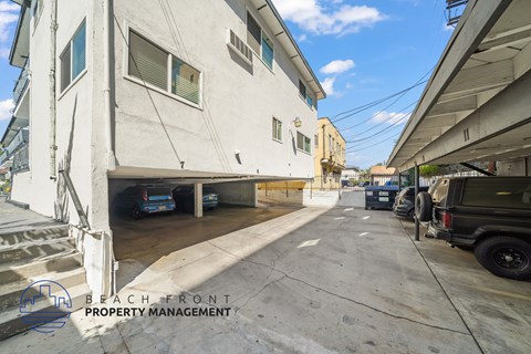 A street view with a white building on the left and a black vehicle on the right.