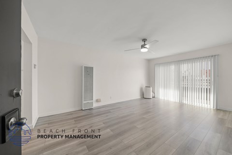 A room with a ceiling fan and a window with blinds.