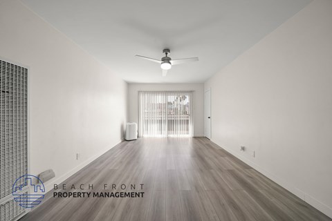 A spacious room with a fan and a window with blinds.