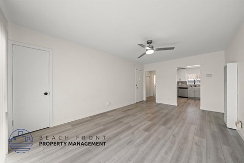 A spacious room with a ceiling fan and wooden flooring.