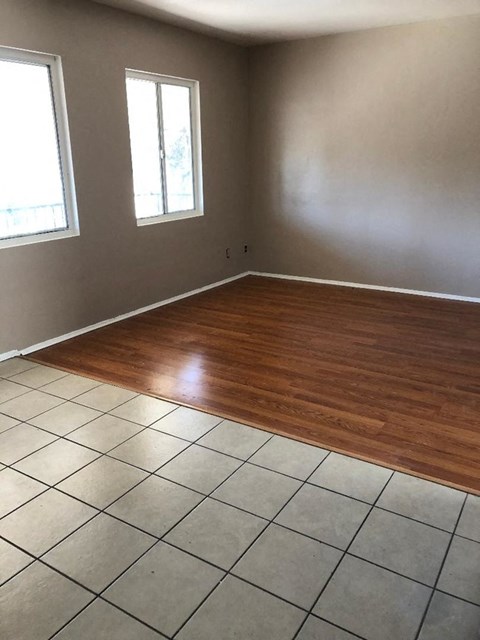 an empty living room with wooden floors and tiled