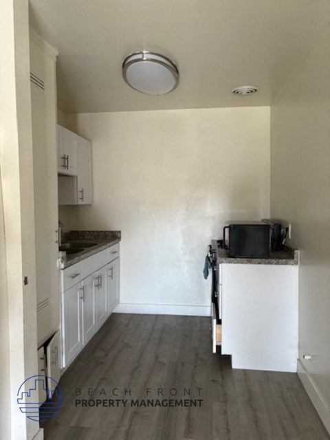A kitchen with white cabinets and a black pot on the counter.