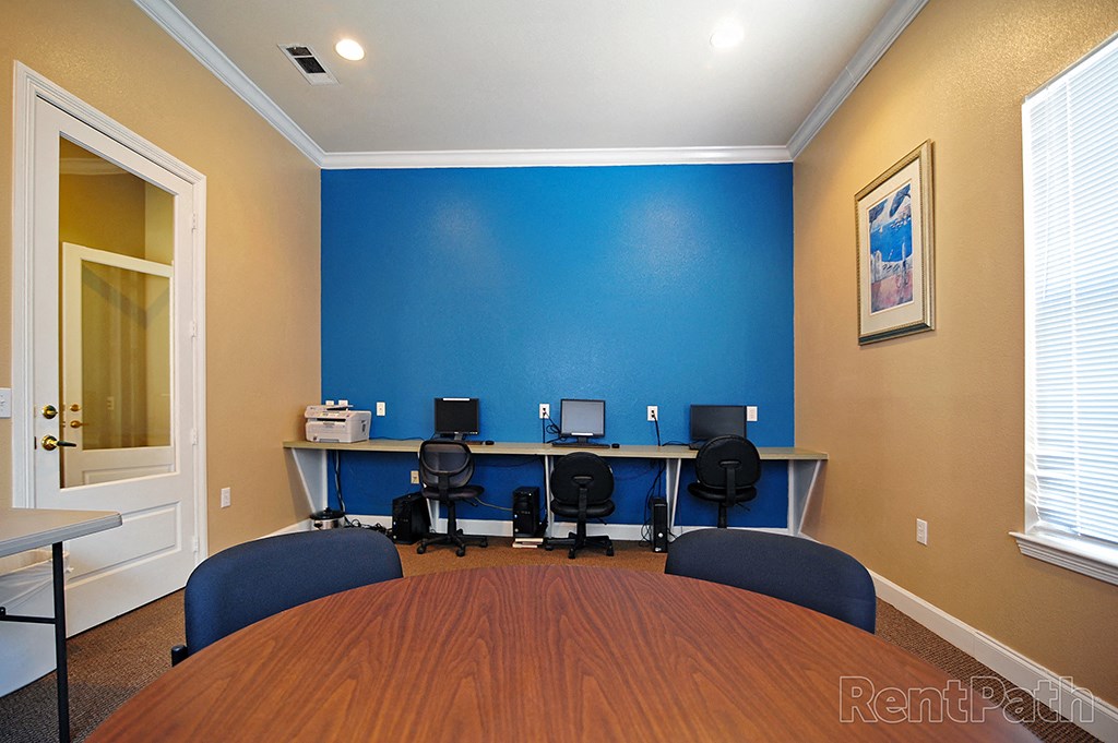 a conference room with three computers and a large table