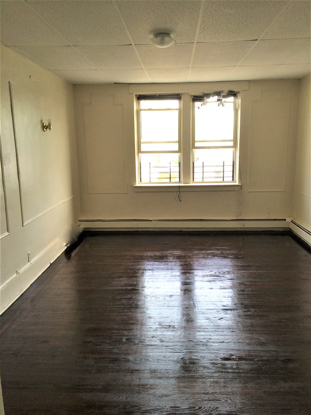 an empty room with a window and wood floors