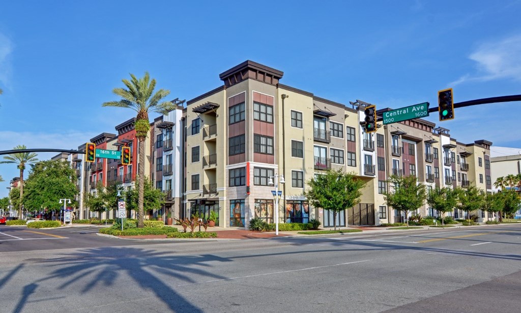 A street view of a multi-story building with a traffic light on the corner.