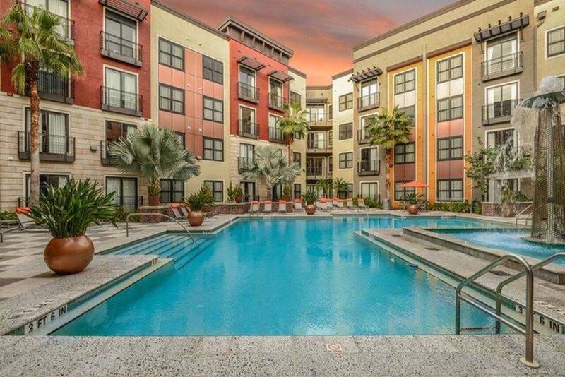 A large swimming pool in front of a multi-story apartment building.
