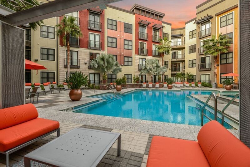 A pool surrounded by orange couches and tables.