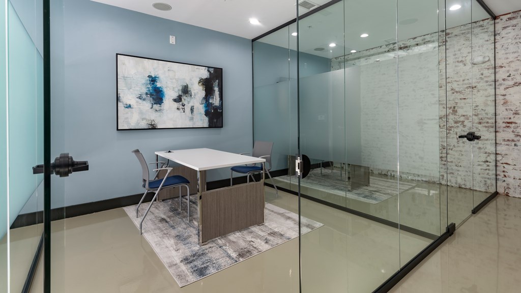 A room with a glass table and a painting on the wall.