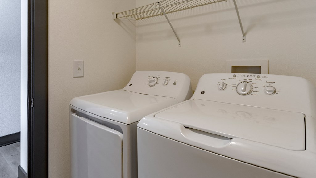 Two white front loading washing machines in a small laundry room.