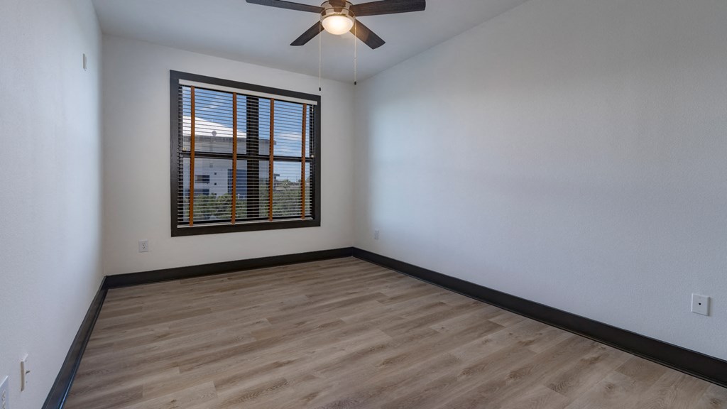 A room with a ceiling fan and a window with blinds.