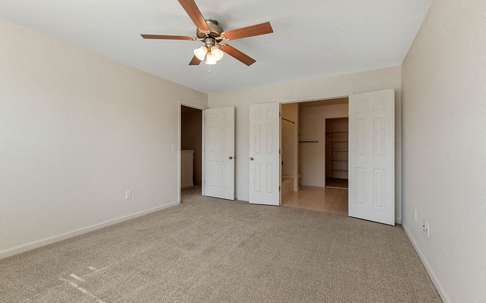 an empty living room with a ceiling fan
