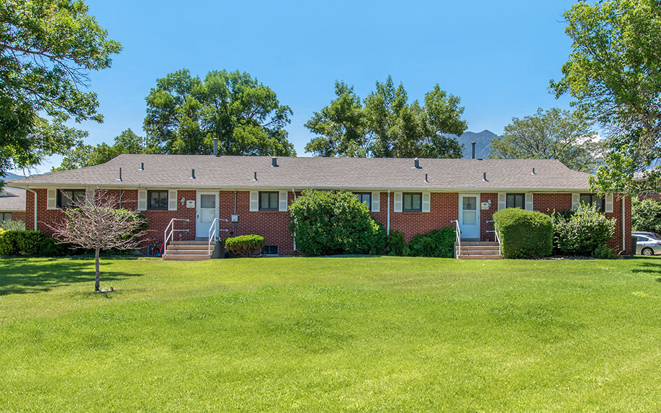 a red brick house with a green lawn in front of it