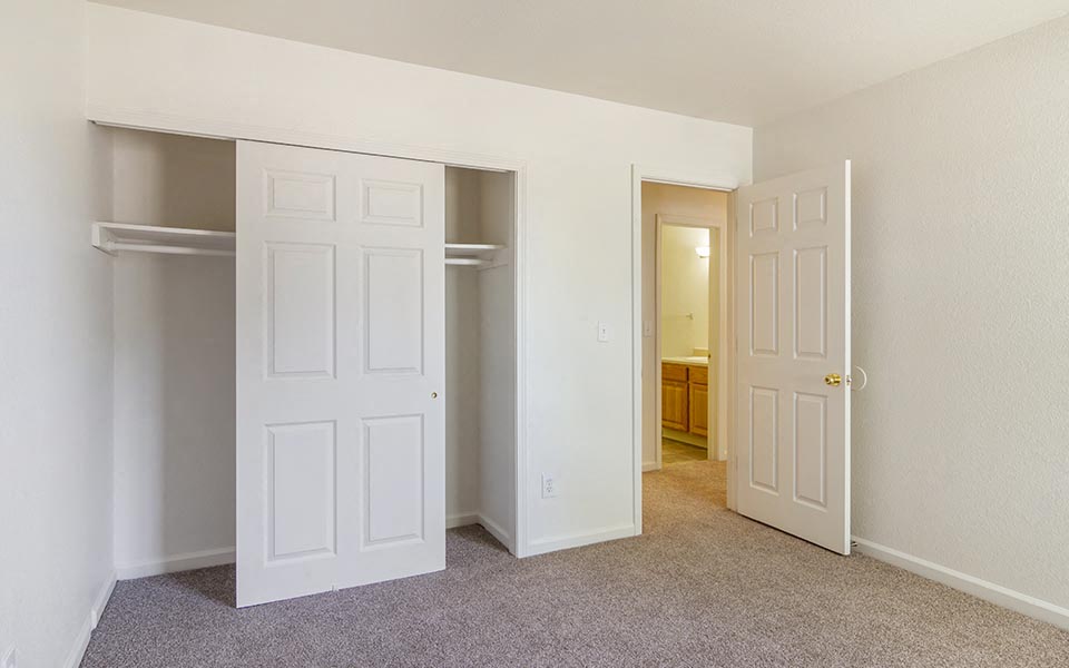 an empty bedroom with two doors and a closet