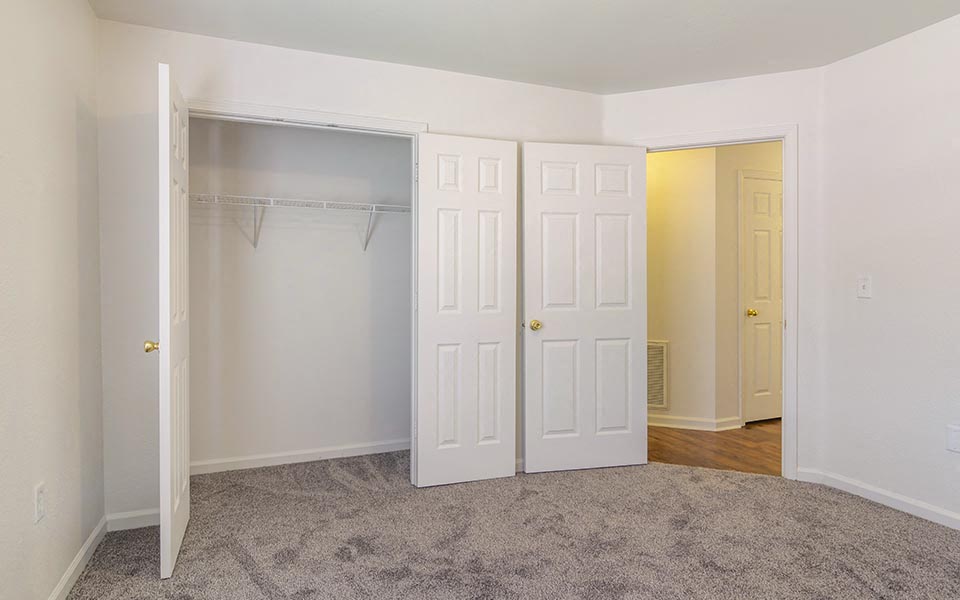 an empty bedroom with white doors and a closet