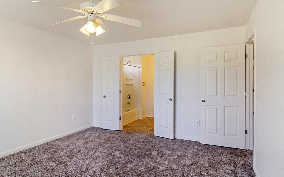 a bedroom with white walls and a ceiling fan     and a closet