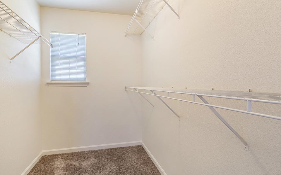 the spacious closet in the upstairs bedroom of a home with a window
