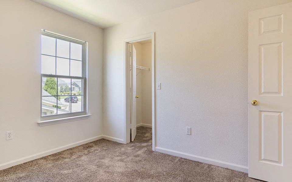 an empty bedroom with a door and a window