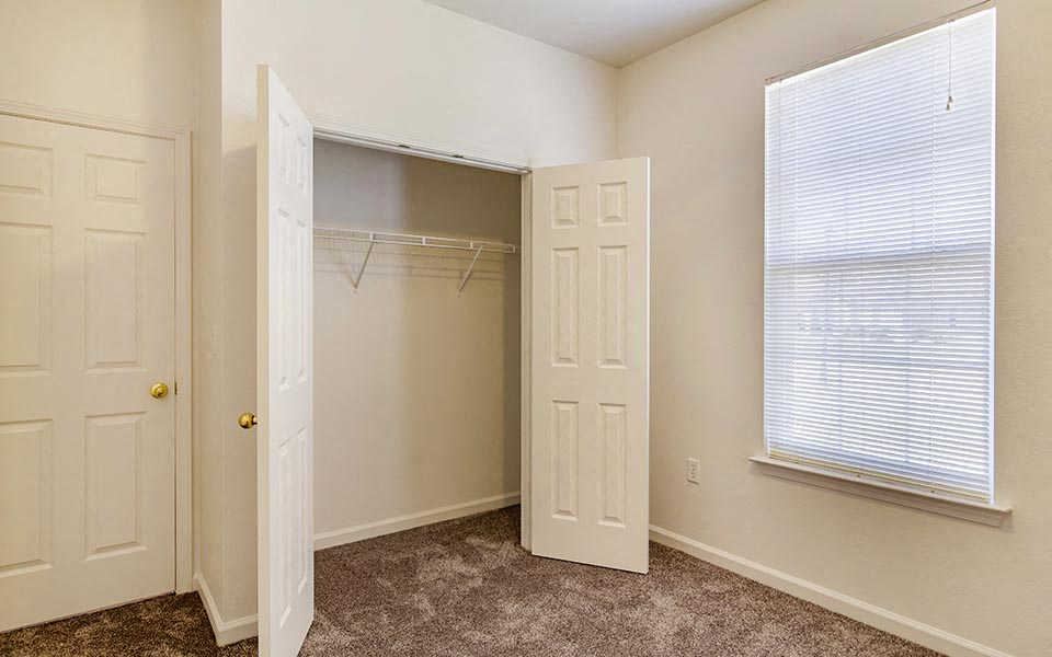 an empty bedroom with a closet and a window