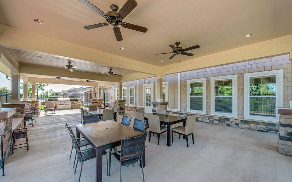 a covered patio with tables and chairs and ceiling fans