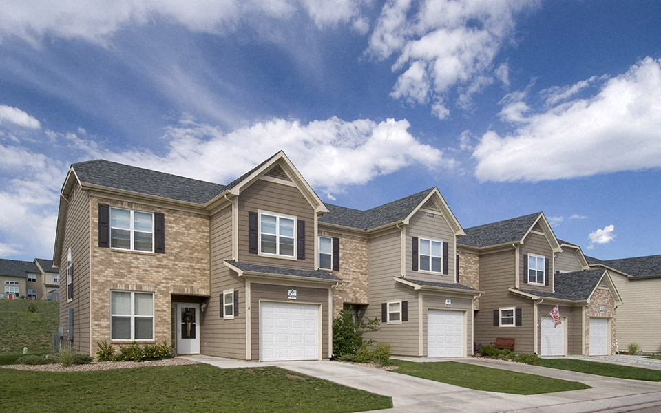a row of houses in front of a blue cloudy sky