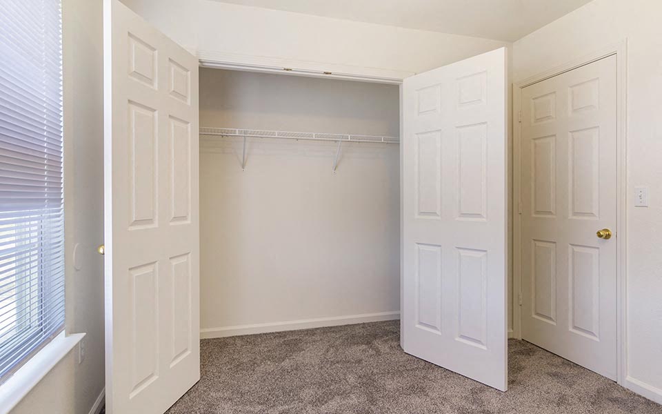 an empty closet with two doors and a window