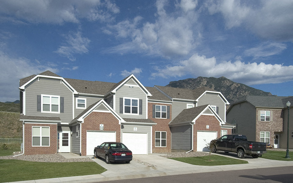 a row of houses with cars parked in front of them