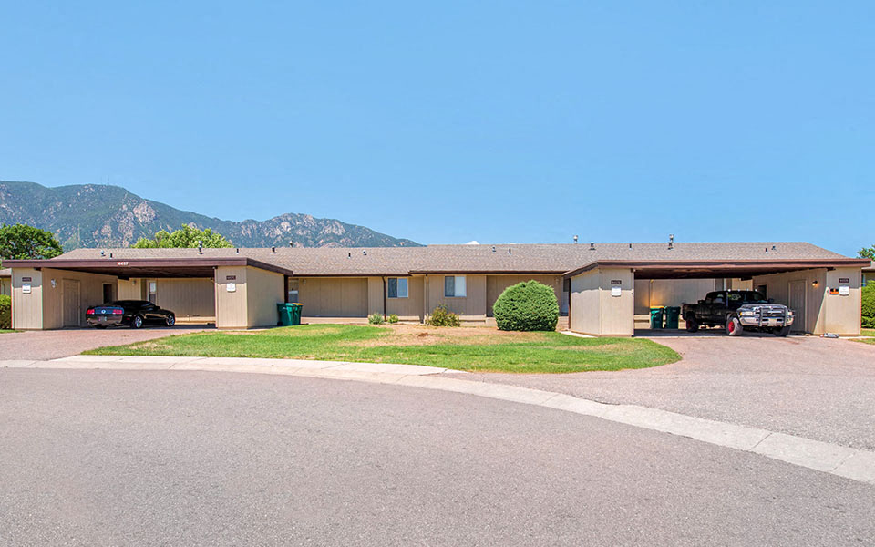 a building with a parking lot and mountains in the background