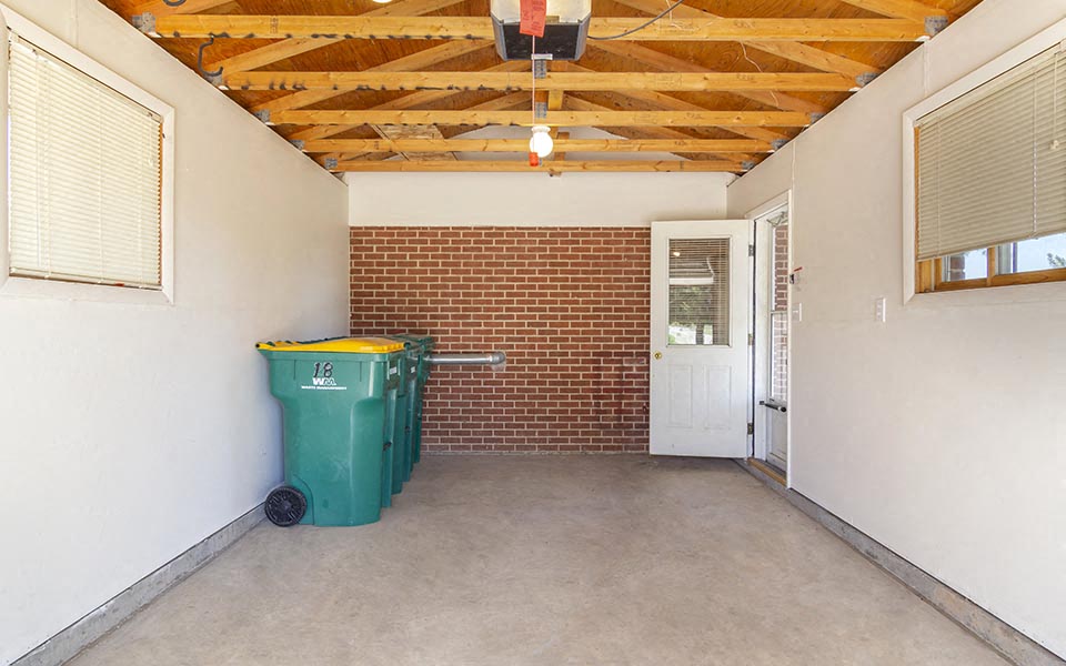 an empty room with a trash can in it and a brick wall