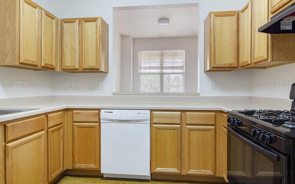 a kitchen with wooden cabinets and a white dishwasher