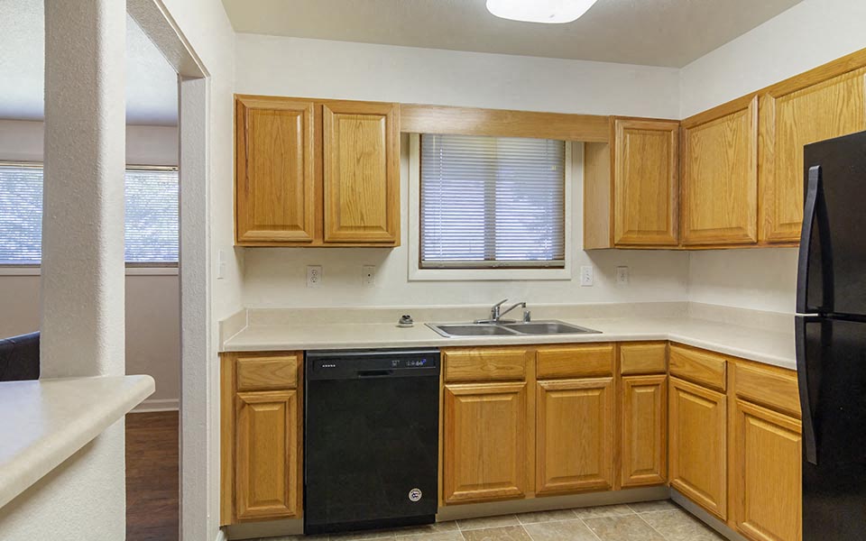a kitchen with wooden cabinets and a black dishwasher
