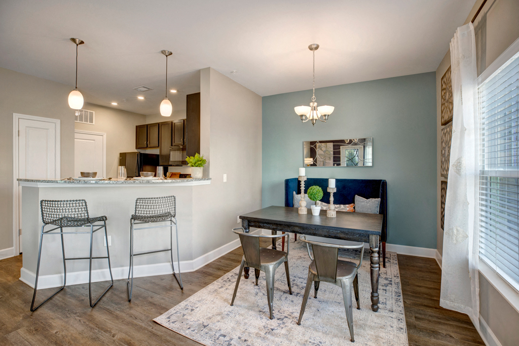 Kitchen with small dining room space. Breakfast bar with stools. Dining area with a table couch and two chairs at at Ascent at Mallard Creek Charlotte, NC
