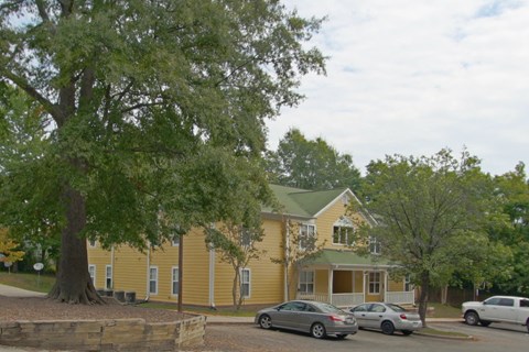 A yellow house with a tree in front of it.