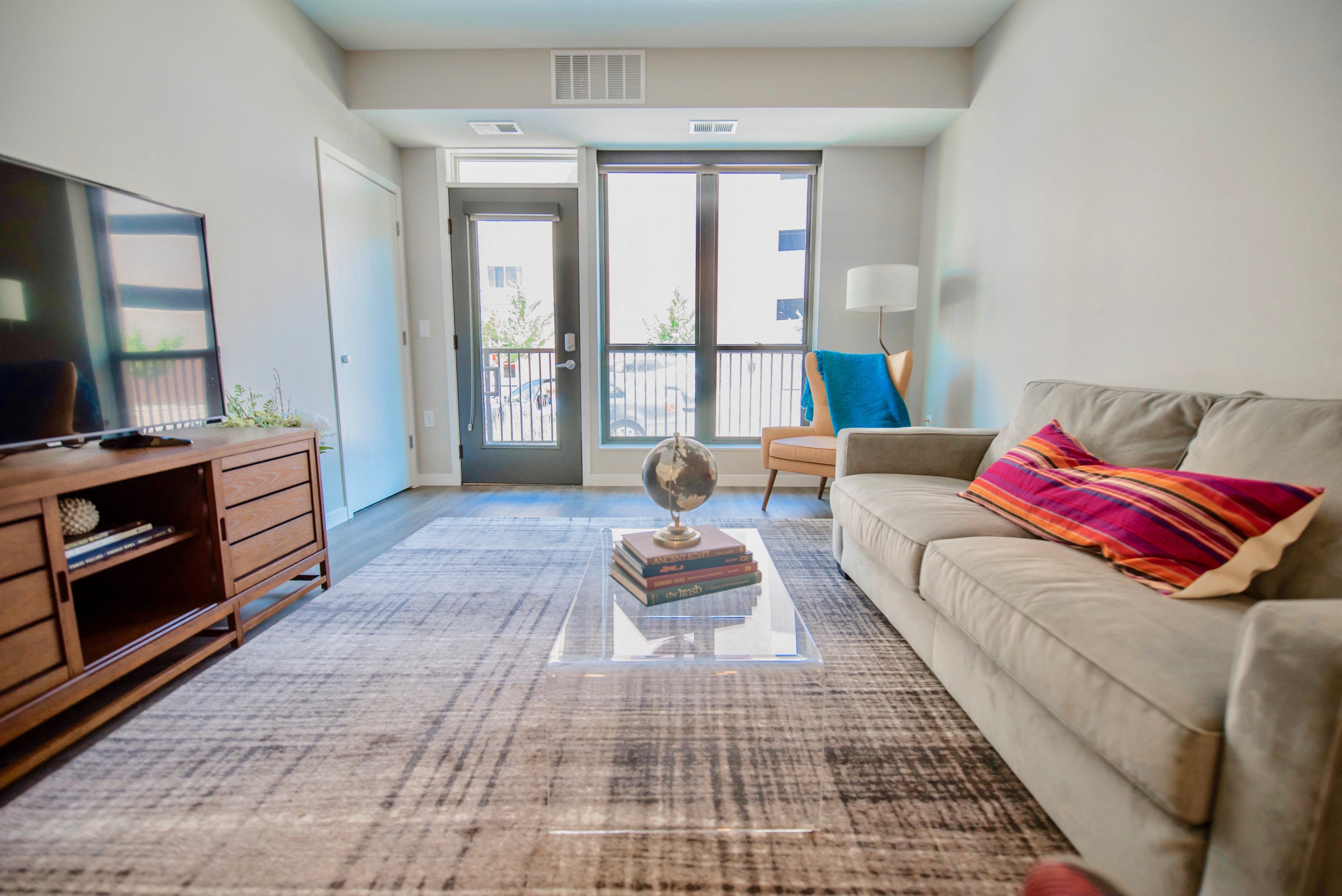 a living room with a couch and a tv and a balcony