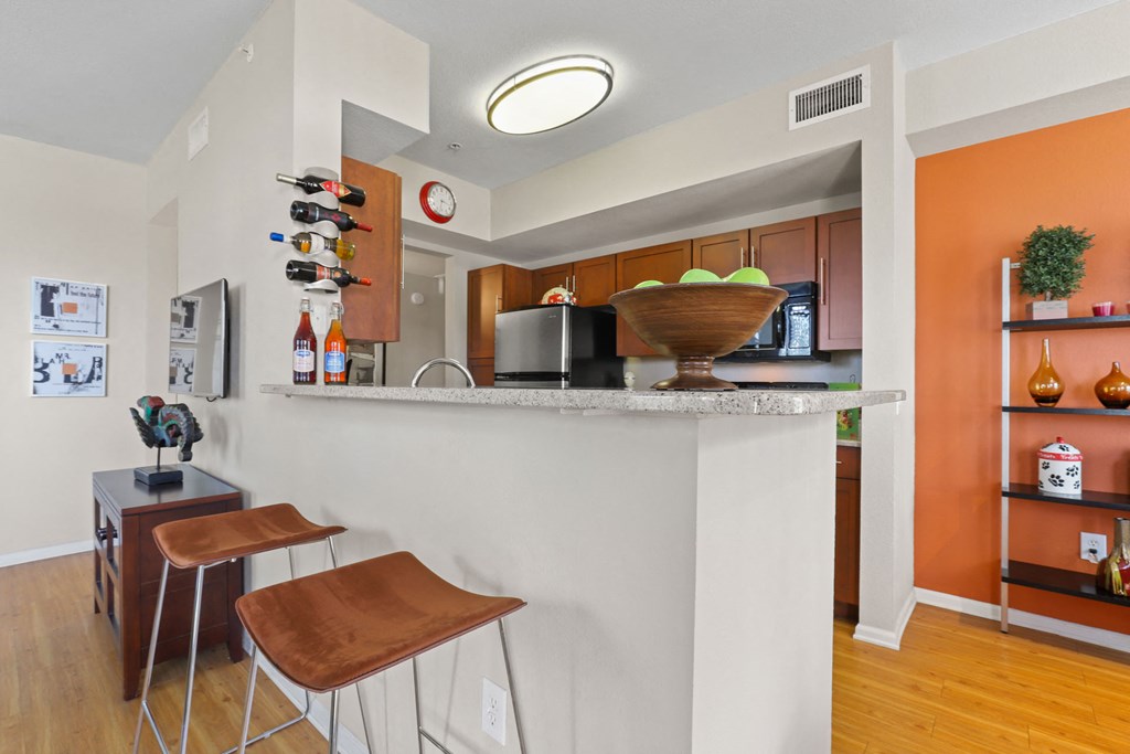 a kitchen with a counter and stools in front of a bar with chairs