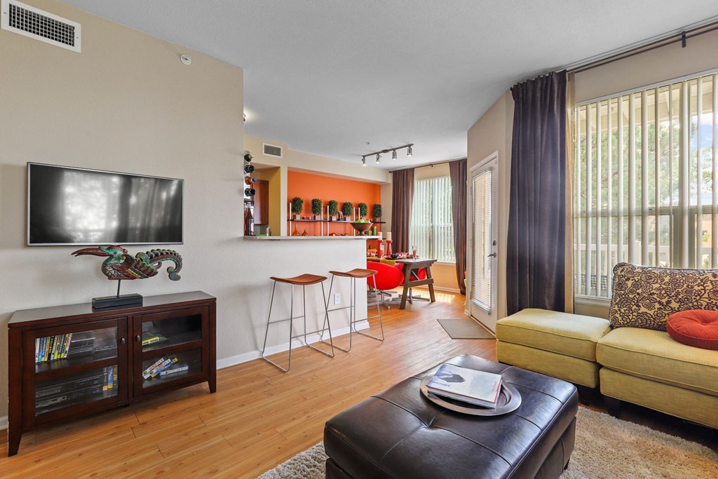 a living room with a couch and a tv and a kitchen with a bar
