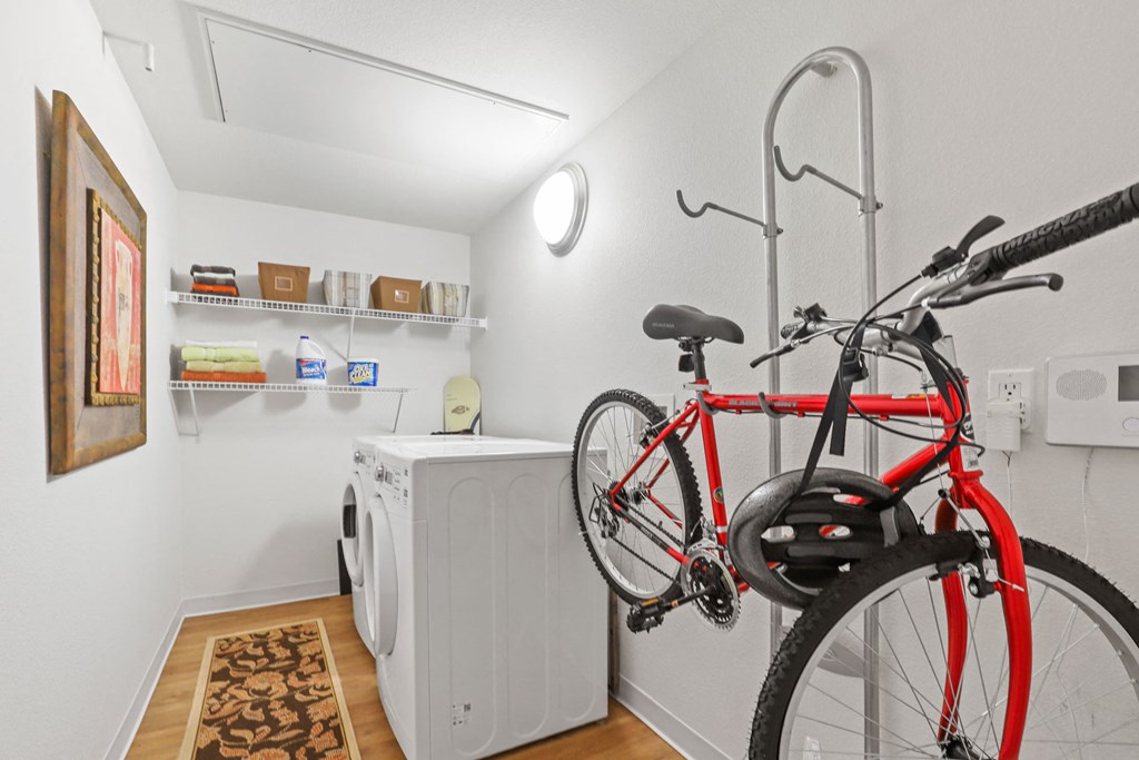 a bike hanging on a wall in a laundry room with a washing machine