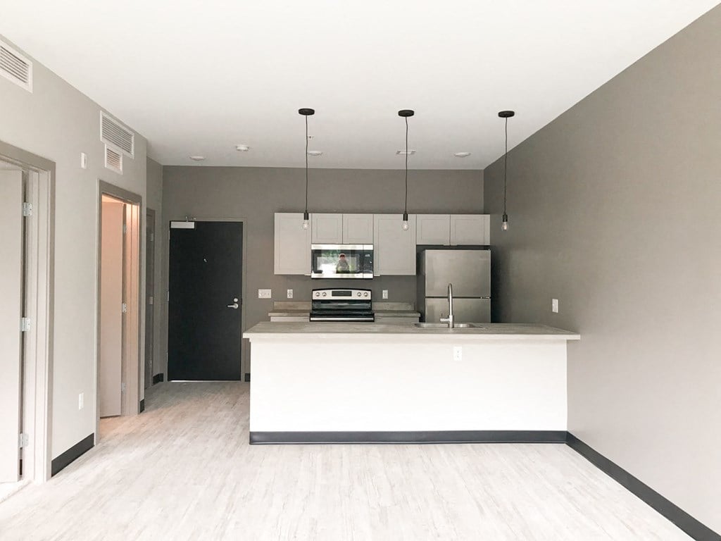 an empty kitchen with a white island and gray walls