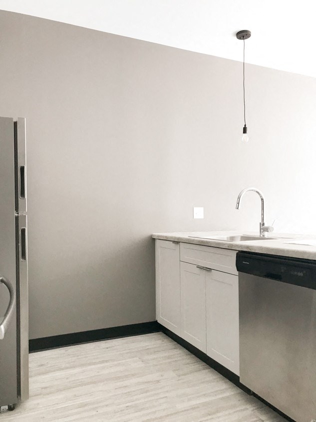 an empty kitchen with white cabinets and a stainless steel refrigerator